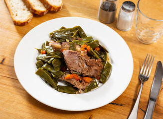 Appetizing beef stew with green beans, carrot and parsley on white plate