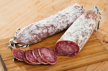Traditional Catalan dry cured pork sausage Longaniza with sliced pieces on wooden board..
