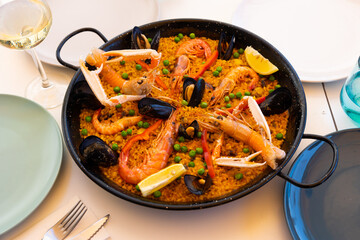 Traditional seafood paella with lobster, mussels, calamari and shrimps in frying pan