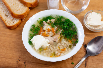Traditional russian soup, rassolnik, served in bowl on table, decorated with parsley