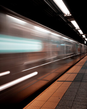 New York City Subway Train Speeds Through Station with Motion Blur at Night
