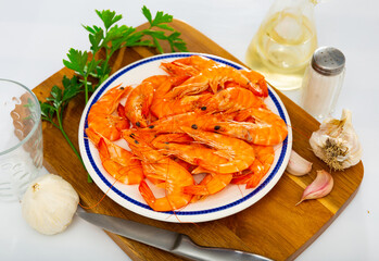 Chilled red whole prawns on plate with spicy garlic, fresh parsley and olive oil prepared for cooking..