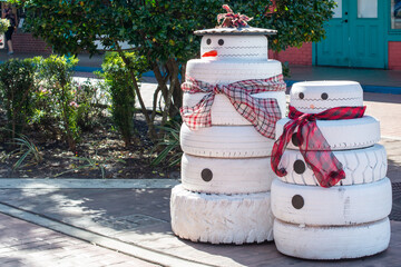 Homemade Christmas snowmen on display. The recycled tires are painted white with black buttons....