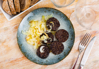 Morcilla con cebolla - fried blood sausage with onion on table. Spanish cuisine