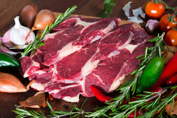 Raw beef meat with vegetables and rosemary on cutting board