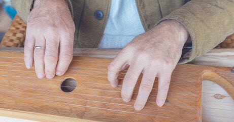 Man is playing a stringed instrument with his hands