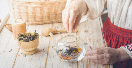 Woman is preparing a tea with a tea pot and a spoon