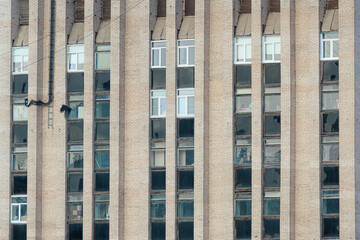 Fototapeta premium Close-up of brick facade with multiple vertical windows on a Soviet-era building in Saint Petersburg, Russia. Urban architecture concept for design and print. Structural elements and symmetry.