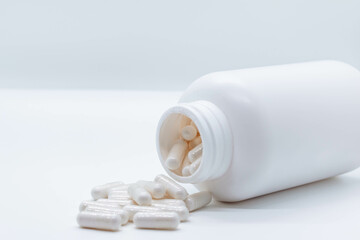 white medicine or vitamin bottle with pills coming out isolated on white background with copy space