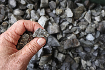 Hand holding a piece of ore mined for silver. Used in jewelry, components in electric vehicles, EVs...