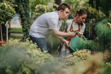 A male with Down syndrome and a female in a wheelchair enjoy a gardening activity together. They...