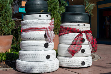 Homemade Christmas snowmen on display. The recycled tires are painted white with black buttons. Both lawn ornaments have scarfs wrapped around the decoration and the taller snowman is wearing a hat. © Dolores  Harvey