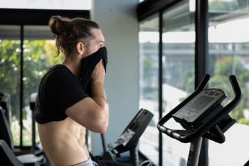 Portrait of caucasian muscular sport man with perfect abs and bicep muscle inside the gym with dark background for cardio exercising and workout in high contrast low key lighting studio