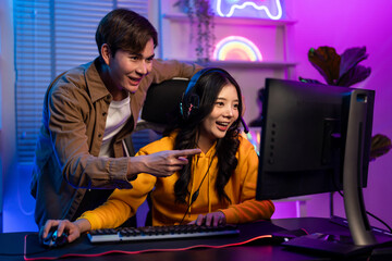 Asian Esport couple gamer playing online video game on computer. 