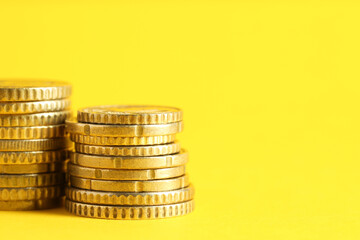 Salary concept. Stacked coins on yellow background, closeup. Space for text