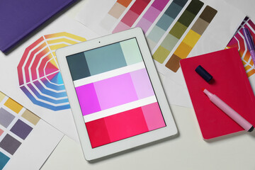 Designer's workplace with tablet, different palettes and stationery on white table, flat lay