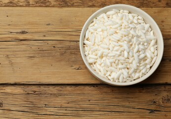 Puffed rice in bowl on wooden table, top view. Space for text