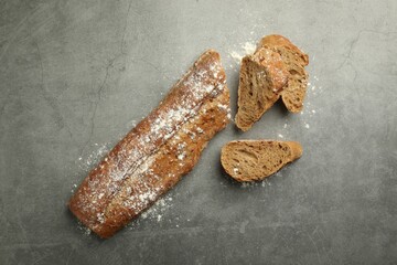 Cut fresh baguette on grey table, flat lay