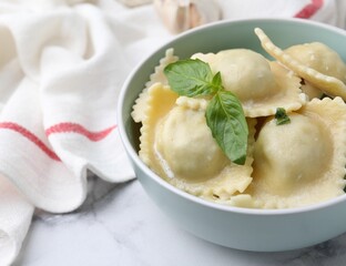 Delicious ravioli with cheese and basil served on white marble table, closeup
