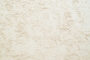 Fototapeta premium A close-up of a textured wall with a cream color. The texture is subtle, almost like a fine sand or small pebbles. The wall is evenly lit and has no shadows.