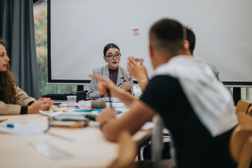 A group of students actively engage in a classroom setting. They listen attentively and discuss ideas, fostering a vibrant educational environment. The focus is on collaborative learning and active