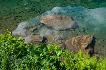 Clear water of Lake Dukka "Rybka" on the Malaya Dukka River on the slopes of the Arkasar ridge in the North Caucasus on a sunny summer day, Arkhyz, Karachay-Cherkessia, Russia © Ula Ulachka