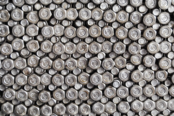A high-resolution image showcasing numerous metallic bolt heads arranged closely, highlighting industrial themes. The image captures the texture and uniformity of the bolted surfaces.