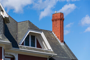 Red brick chimney and gable dormer on a historic house roof in Brighton, Massachusetts, USA

