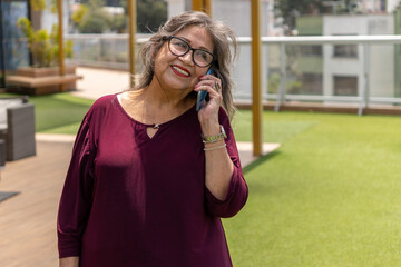 Attractive smiling senior woman talking on cell phone in a garden