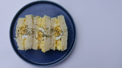 group of slices of bread with meat filling, eggs on a blue plate, green background