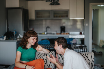 A cheerful moment between two friends laughing and enjoying a relaxed time in a comfortable home setting. Capturing joy, friendship, and the simplicity of shared moments.