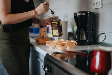 A woman is making coffee in a modern kitchen, using a coffee jar and ceramic cups. The setting is homey, emphasizing relaxation and everyday routines.