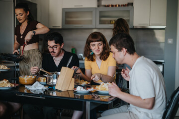 A group of friends having a casual and joyful dining experience around a table with homemade food, emphasizing companionship and comfort in a cozy kitchen setting.