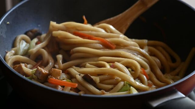 Stir fried udon noodles with tofu, vegetables and soy sauce in pan, Yaki udon noodles cooking, Japanese cuisine