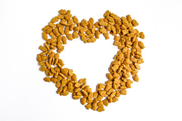 Pile of dry cat food in heart shape isolated on white background