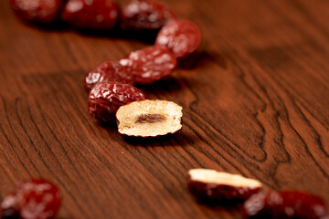 Dried red dates, or jujubes, rest on a wooden surface, commonly used for their sweetness and health benefits.