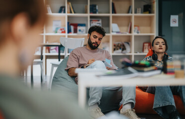 A relaxed group meeting with a professor and college students in a modern library setting, emphasizing learning and collaboration.