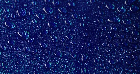 Humidity surface. Drop stream. Transparent dew on smooth blue area. Watery dark background with...
