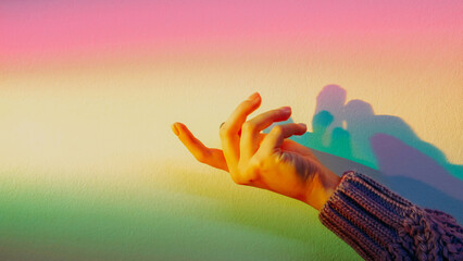 Spiritual energy hand. Advertising background. Rainbow pastel. Female fingers on blur glowing color gradient light wall with copy space.