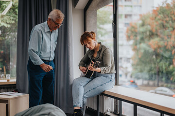Senior professor guides a young student playing guitar in a contemporary classroom. The scene...