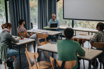 Group of students attentively listening to a professor in a warm and inviting classroom setting. Educational session focuses on engaging discussion and learning.