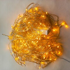 A coil of yellow LED garland on a white background. The included diode lights of the garland are...