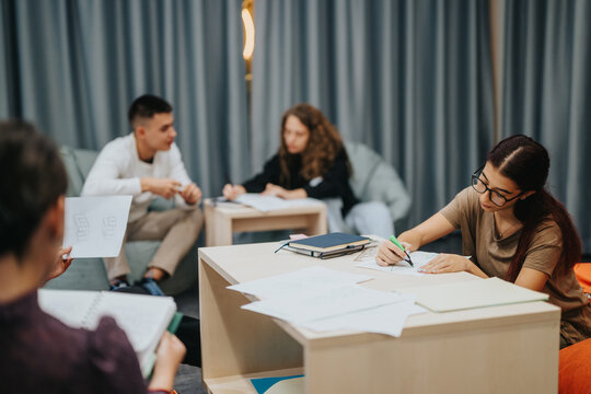 A group of students working together on assignments at school, showcasing collaboration and study in a relaxed, modern learning environment.