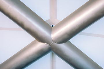 Naklejka premium Metallic intersecting pipes creating a geometric pattern in an industrial setting