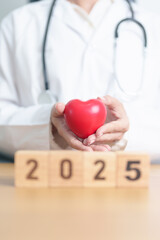 Happy New Year 2025 with doctor holding red heart shape on table. health care, Insurance, donation,...