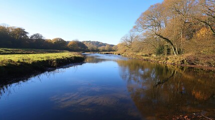 serene river reflecting autumn foliage under clear blue sky