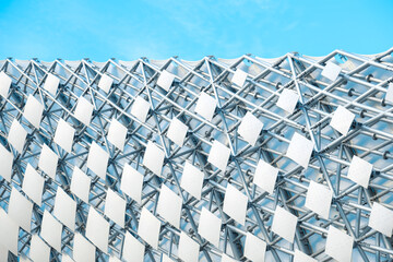 Modern architectural design featuring a lattice structure against a clear blue sky in an urban...