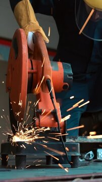 Professional mechanic is cutting steel metal with rotating diamond blade cutter. Steel industry and workshop concept.