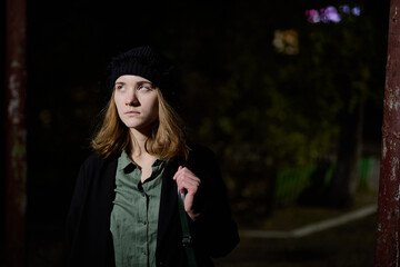 Portrait of a teenage girl dressed in black clothes against the backdrop of a night city,...