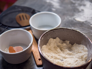 Flour, eggs, and utensils spread across flour-dusted countertop suggest cookie-making in progress. This cozy scene captures all essentials for cookie-making